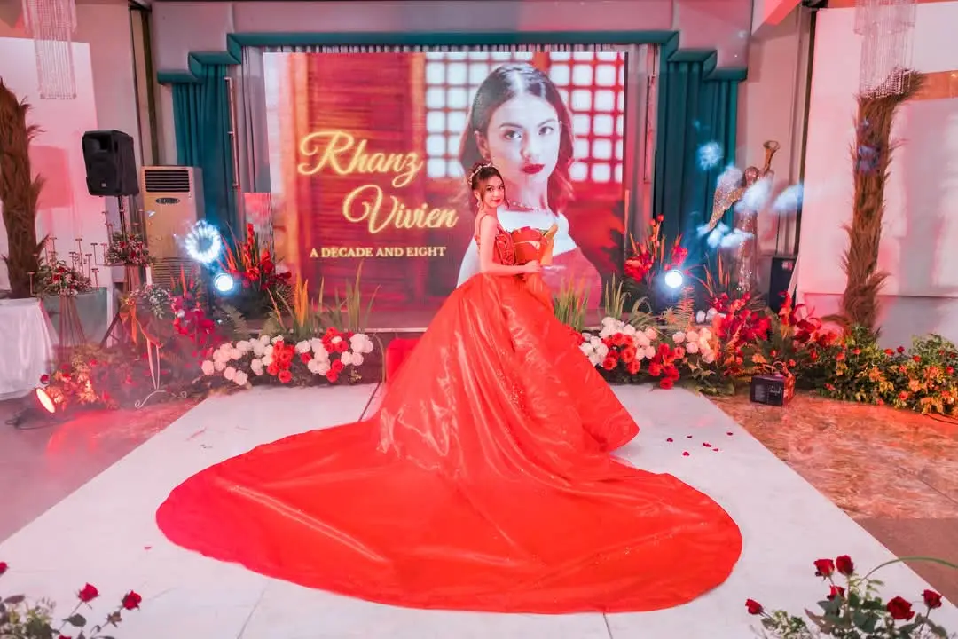 Red gown with a long train on a debut stage