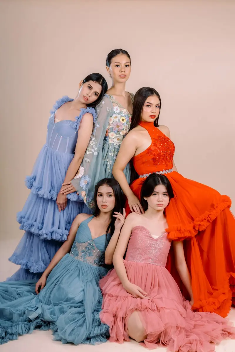 Five women in pastel tiered gowns